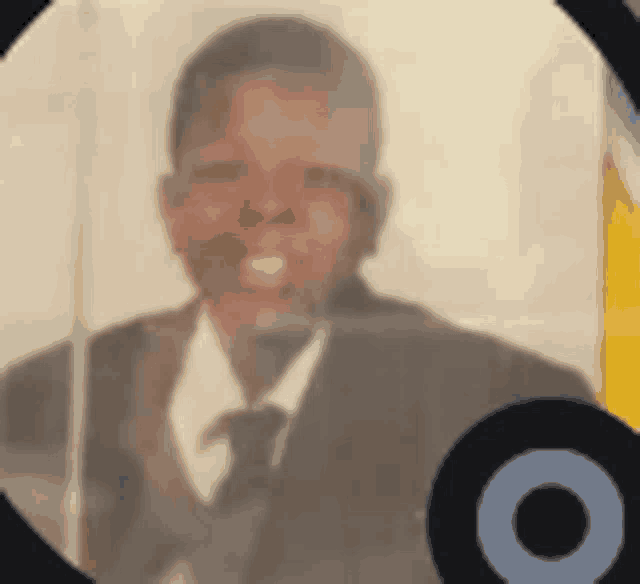 a blurry picture of a man in a suit and tie behind a glass barrier .