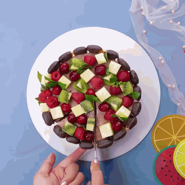 a person is cutting a piece of cake with fruit on it