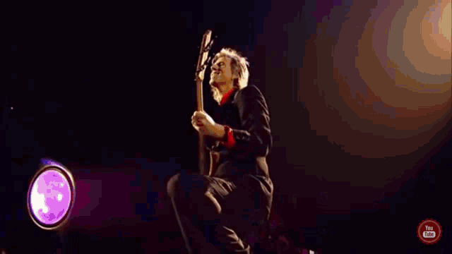 a man in a white suit is running on a stage with a youtube logo in the corner