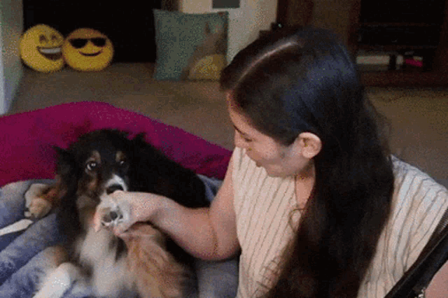 a woman is petting a dog on a bed