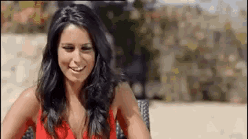 a woman in a red dress is sitting on a chair and smiling .