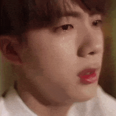 a close up of a young man 's face with a tear coming out of his eye .