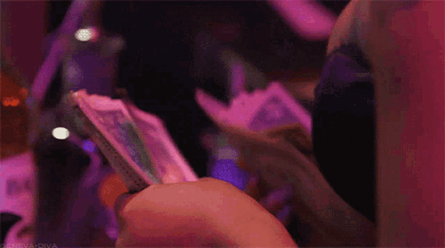a person is holding a bunch of money in their hands with a pink background