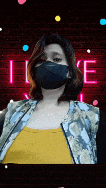 a woman wearing a face mask is standing in front of a neon sign that says i love