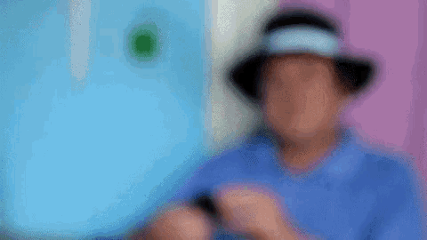 a man wearing a hat is using a cell phone .