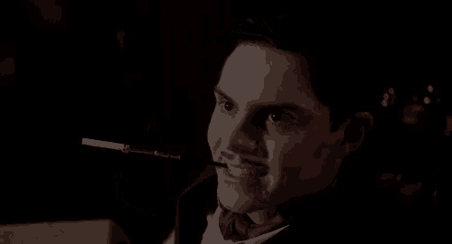 a man in a tuxedo is smoking a cigarette with a ring on his finger