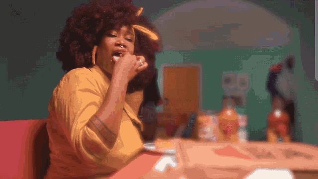 a woman in a yellow shirt is sitting at a table with a plate of food