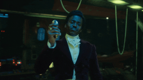 a man in a tuxedo and bow tie holds a light bulb in his hand