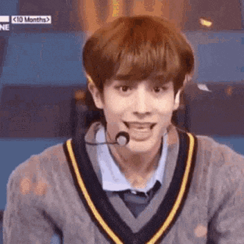 a young man is wearing a sweater and a microphone .