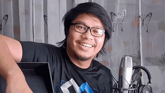 a man with glasses is smiling in front of a microphone
