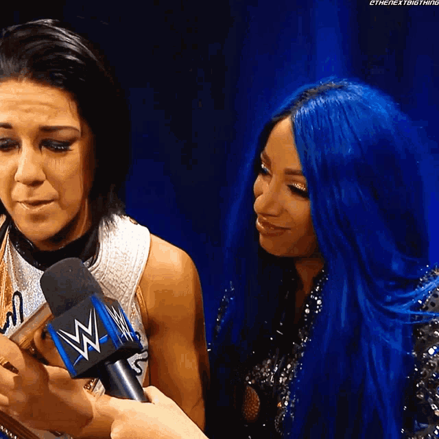 a woman with blue hair is talking into a microphone with a wwe logo on it