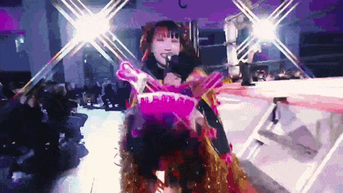 a woman singing into a microphone in front of a crowd of people
