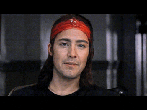 a man with long hair is wearing a red bandana on his head