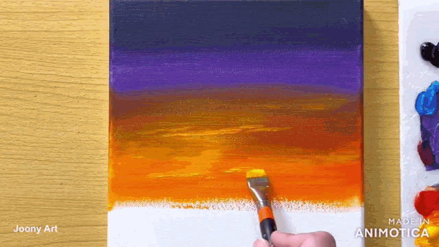 a person is painting a sunset on a canvas with a brush ..