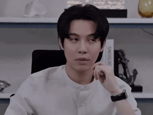 a man in a white shirt sits in front of a book titled designs