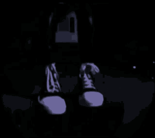 a person 's feet are shown in a dark room with a house in the background .