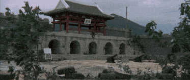 a man stands in front of a building with chinese writing on the top