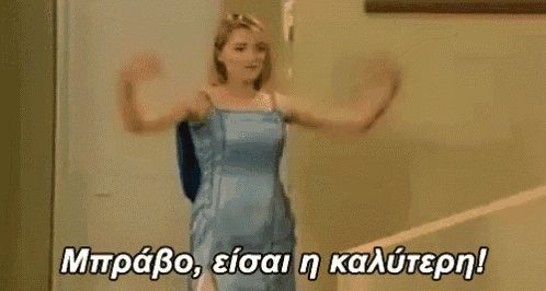 a woman in a blue dress is standing on a staircase with her arms outstretched in a room .