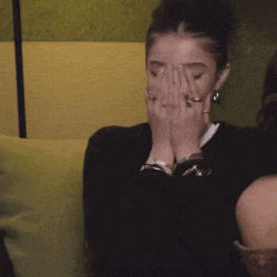 a woman with rings on her fingers is covering her face with her hands .