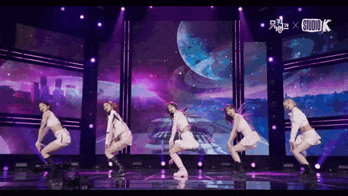 a group of girls are dancing on a stage in front of a studio x sign