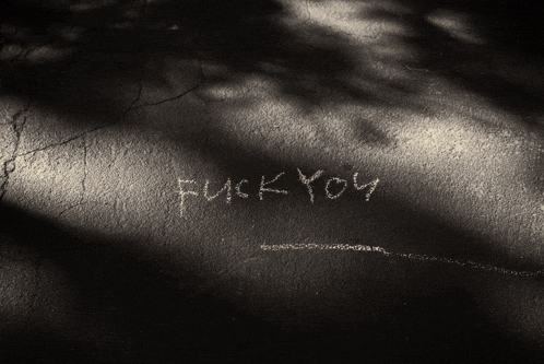 a black and white photo of the word fuck you on a wall