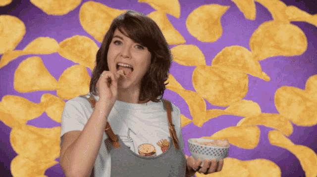 a woman is eating potato chips and holding a bowl