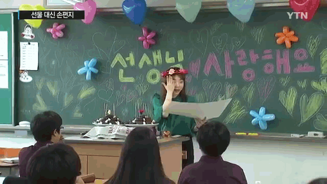 a woman stands in front of a blackboard that says ytn on the bottom