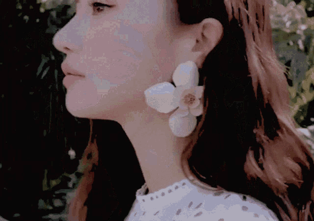 a close up of a woman 's face with a flower earring