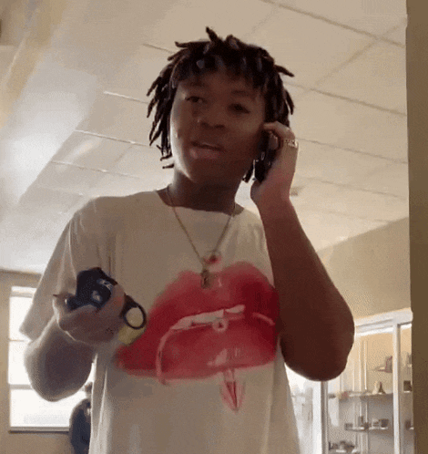 a young man wearing a rolling stones t-shirt is talking on his cell phone