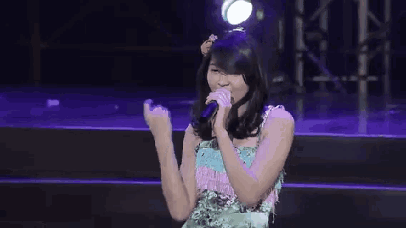 a woman singing into a microphone on stage