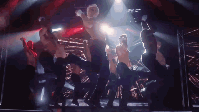 a group of men are dancing on a stage in a dark room