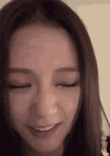 a close up of a woman 's face with her eyes closed and smiling