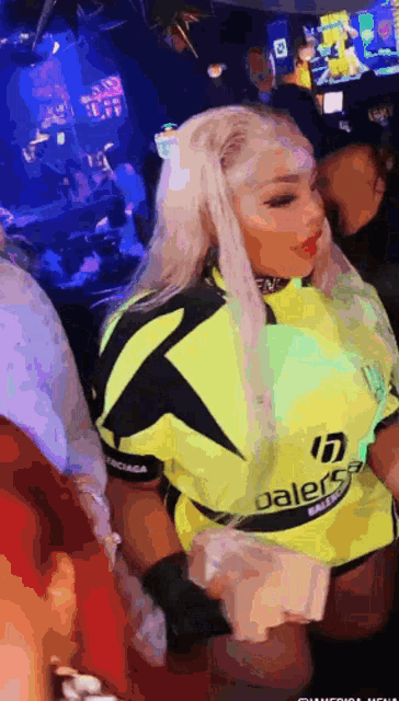 a woman in a neon yellow balenciaga shirt holds a stack of money
