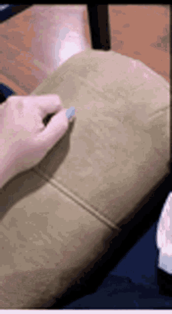 a person is sitting on a couch holding a pillow in their hand .