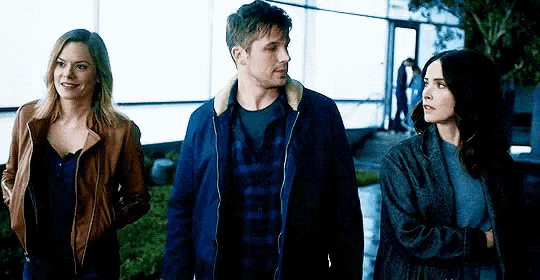 a man and two women are standing next to each other and talking .