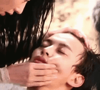a woman is putting her hand on a man 's mouth .