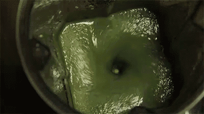 a close up of a green liquid in a blender with a spoon .