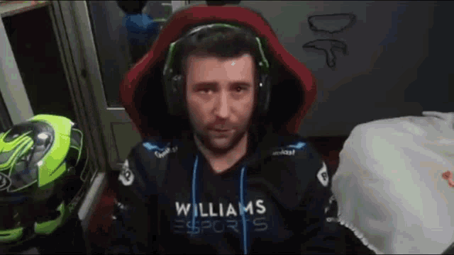 a man wearing headphones and a williams esports hoodie