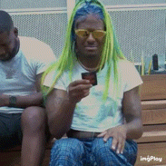 a woman with green hair is sitting on a bench holding a cup