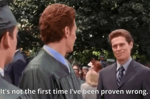 a man in a graduation cap and gown is standing next to a man in a suit and tie .