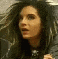a close up of a woman 's face with long black hair and a surprised look on her face .