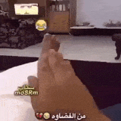 a person is sitting on a bed with their feet up in front of a tv .
