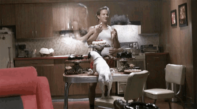 a man and a dog are standing in a kitchen with a cake on the counter