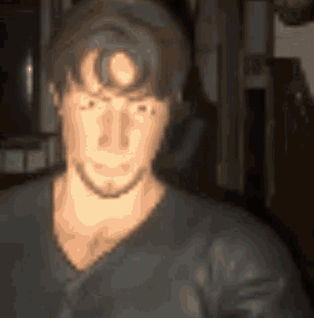 a blurry picture of a man 's face with a circle in the middle of his forehead