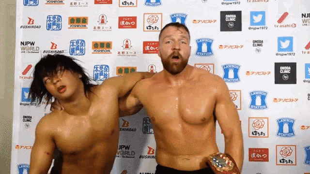 two wrestlers pose in front of a wall with logos for lawson station and njpw world