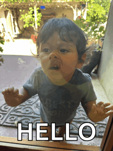 a baby is looking out a window with the words hello written on the glass