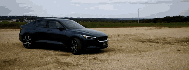 a black car is parked on a dirt road