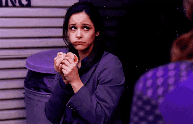 a woman in a purple suit is eating a donut