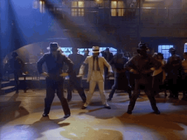 a man in a white suit is dancing with a group of men