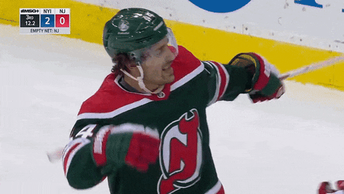 a hockey player in a green and red jersey holds a hockey stick